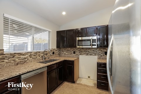 the kitchen has granite counter tops and black cabinets and stainless steel appliances