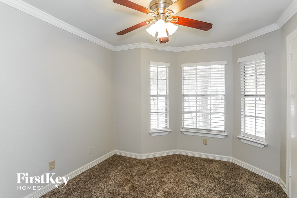a living room with a ceiling fan and three windows