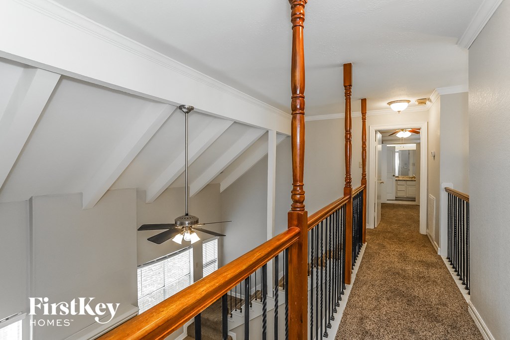 a hallway with a wood railing and a ceiling fan