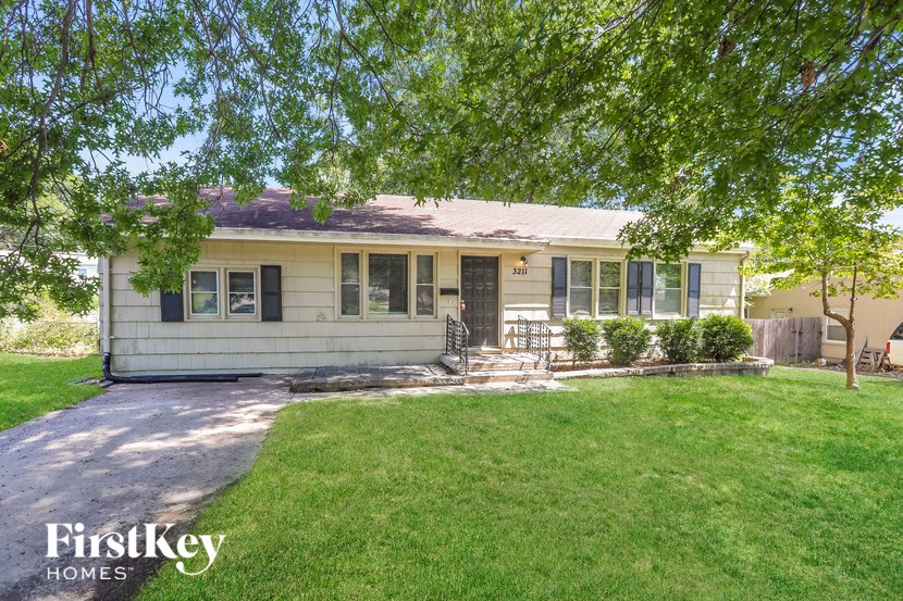 A house with a well-maintained lawn and trees in the front yard.