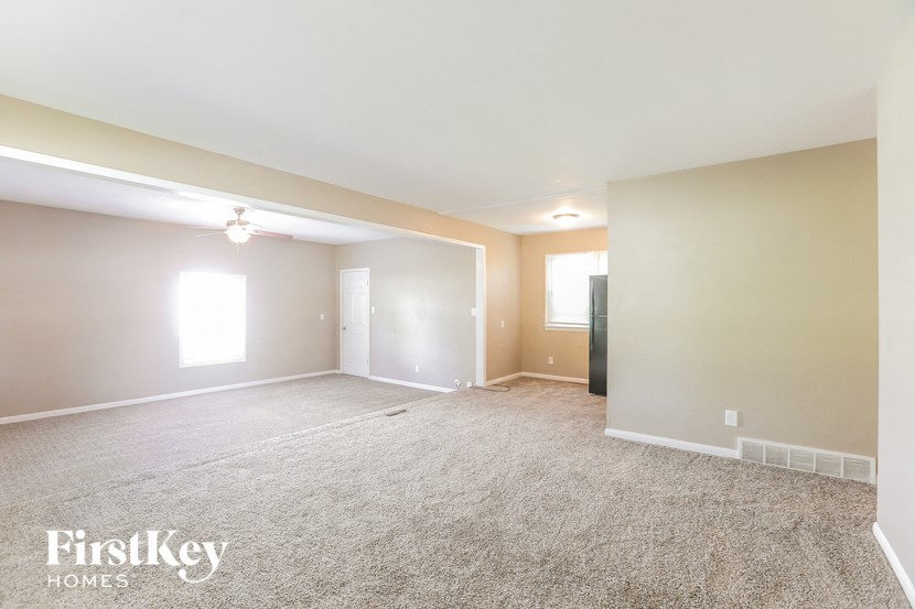 A spacious room with a carpeted floor and a window letting in natural light.