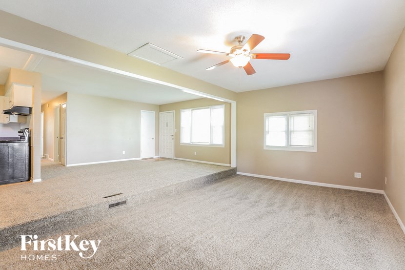 A spacious room with a ceiling fan and carpeted floor.
