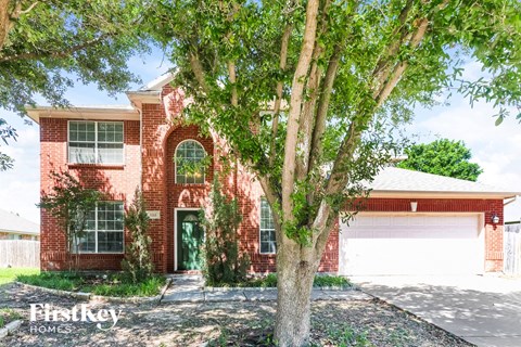 A red brick house with a tree in front.