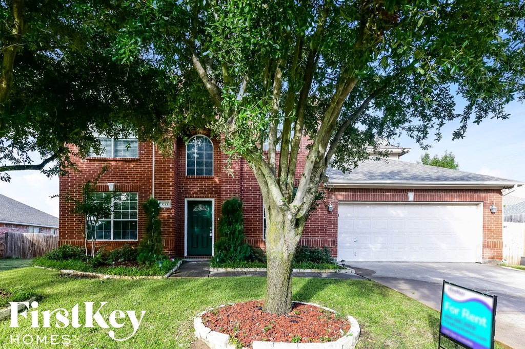A brick house with a tree in front of it and a sign that says FirstKey Homes.