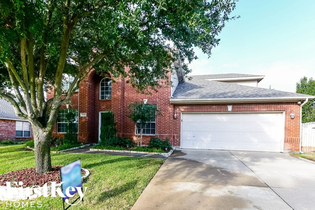 A house with a garage and a tree in front.