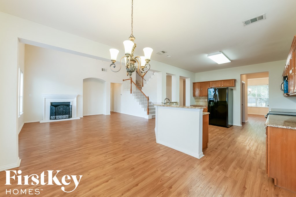 A large empty room with wooden floors and a chandelier hanging from the ceiling.