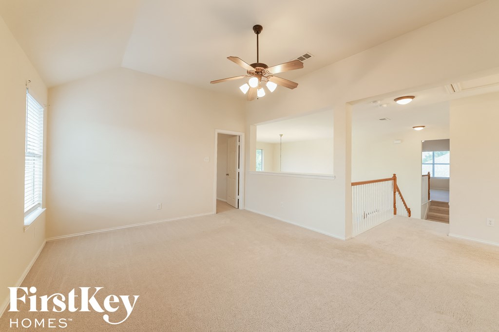 A spacious room with a ceiling fan and carpeted floor.