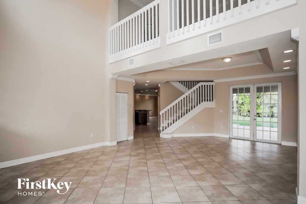 a large empty living room with a staircase and a door