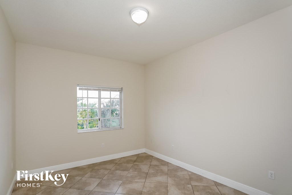 the living room of a home with white walls and a window