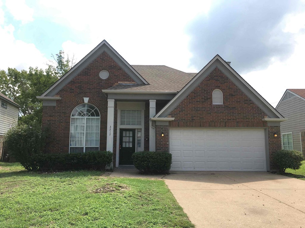 the front of a brick house with a white garage door