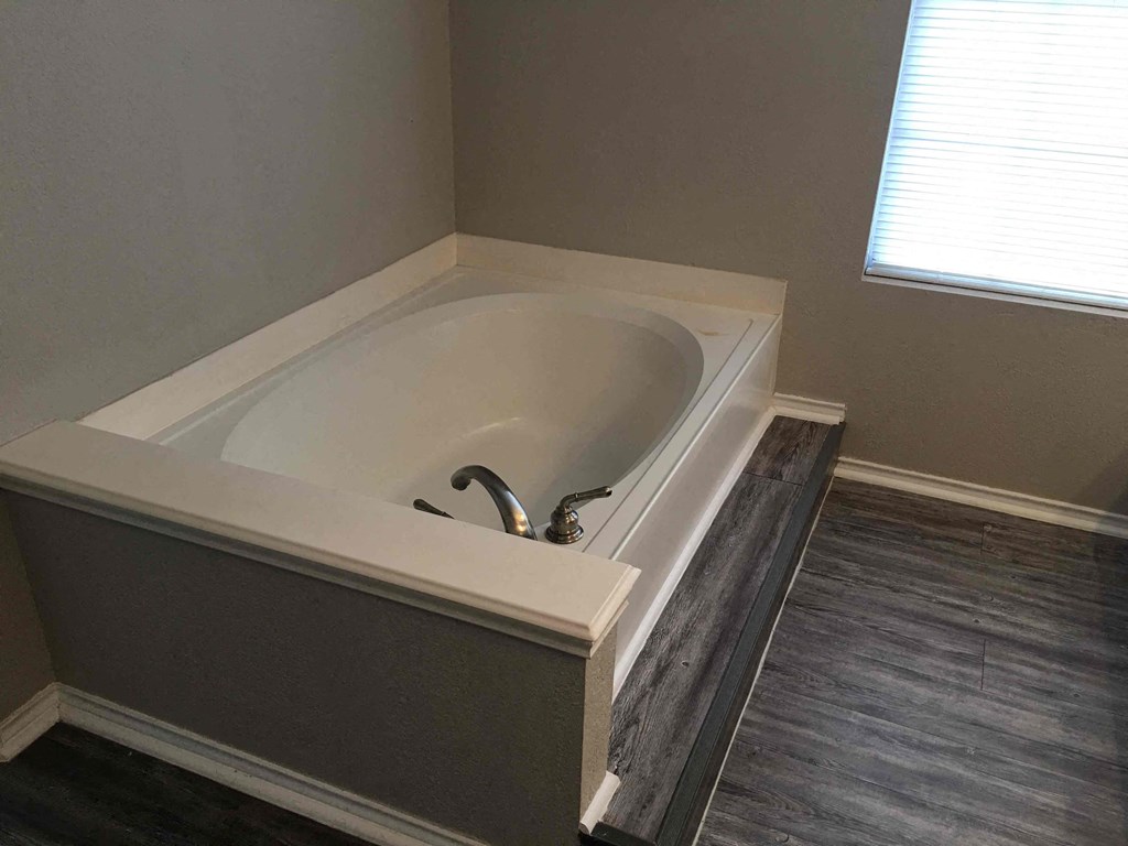 a large bath tub in a bathroom with wood floors