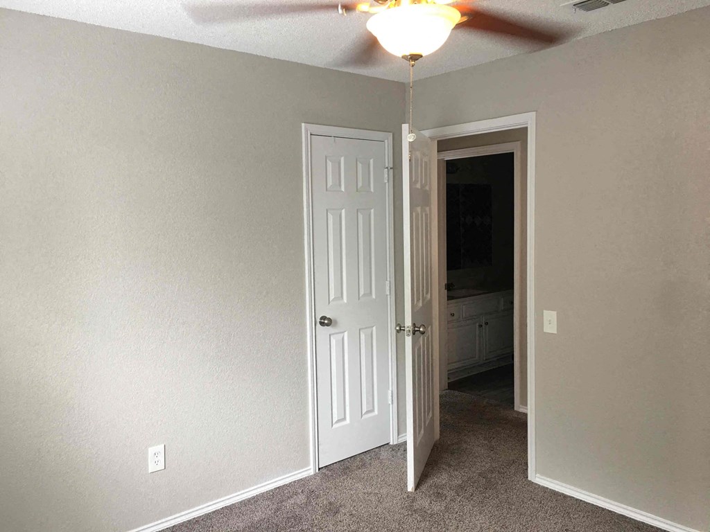 an empty room with a white door and a ceiling fan