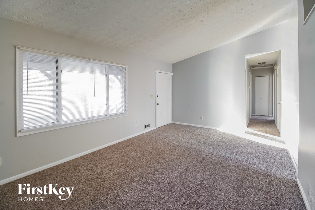 A room with a carpeted floor and a door leading to another room.