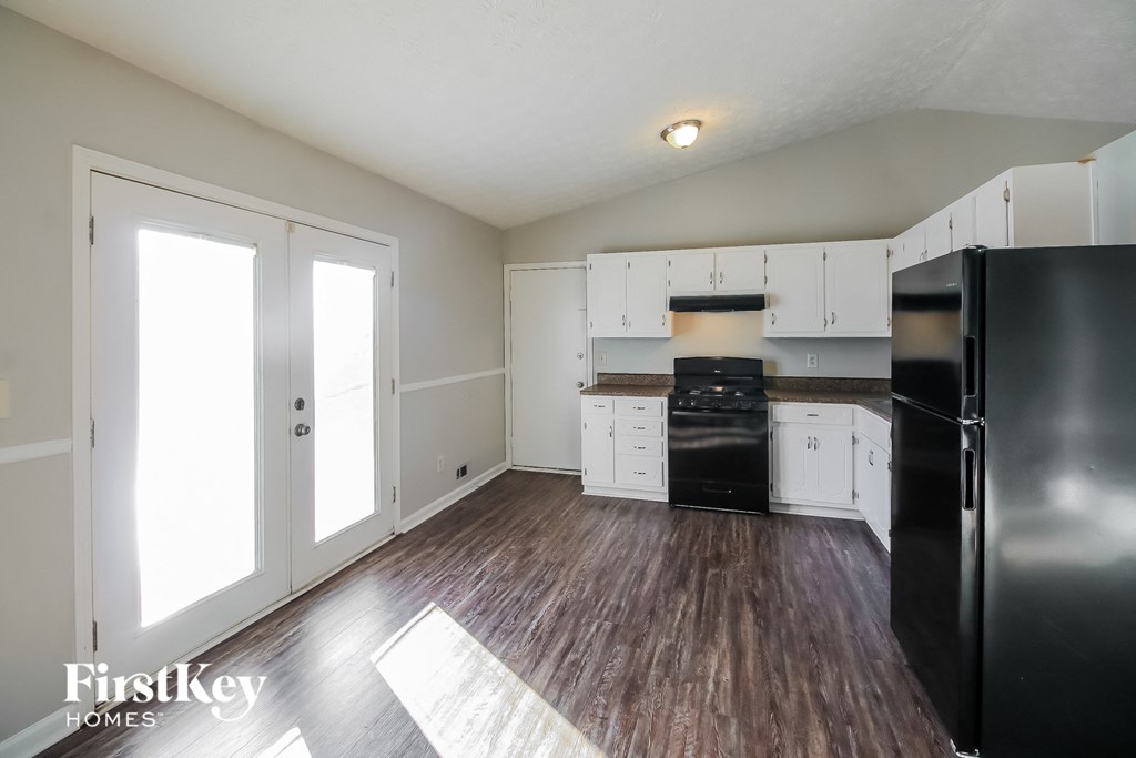 A kitchen with a black fridge and white cabinets.