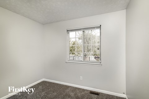A room with a window showing a view of trees and a house.
