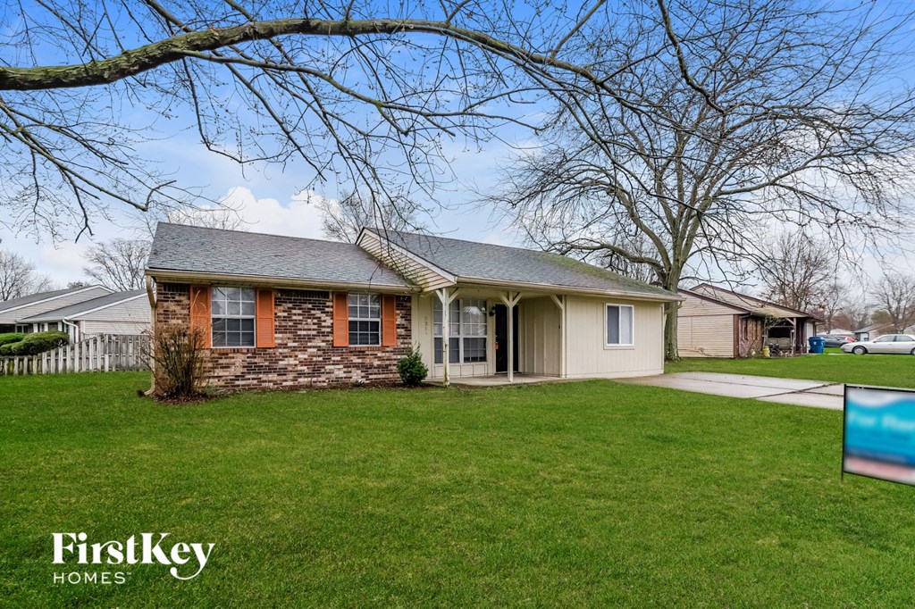a brick house with a yard and a pool in front of it