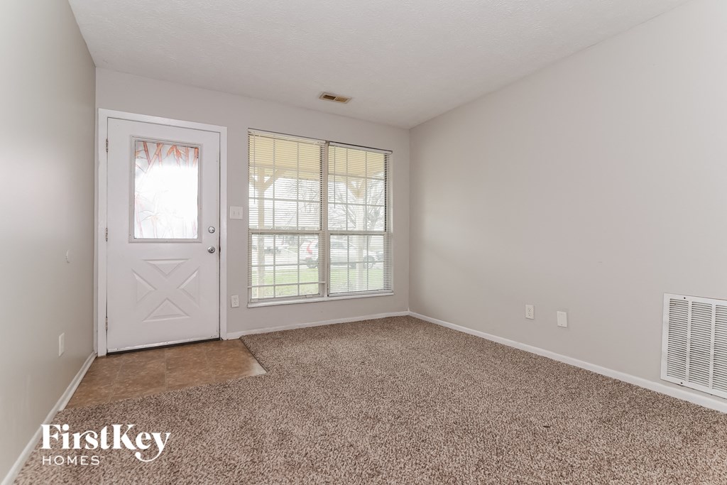 the living room of an empty house with a white door and carpet
