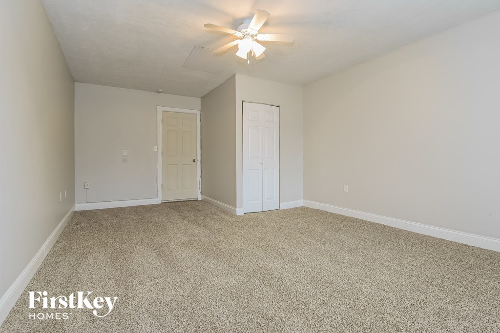 the living room of an empty house with carpet and a ceiling fan