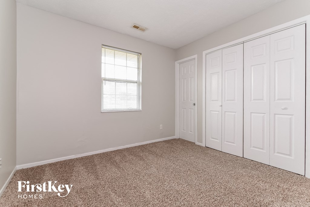 a bedroom with two closets and a window and a carpeted floor