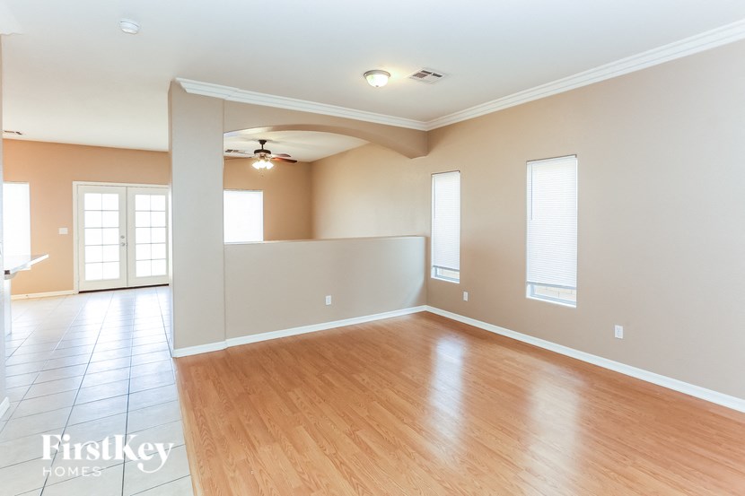 A spacious room with wooden floors and a ceiling fan.