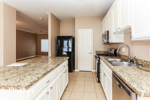 A kitchen with granite countertops and white cabinets.