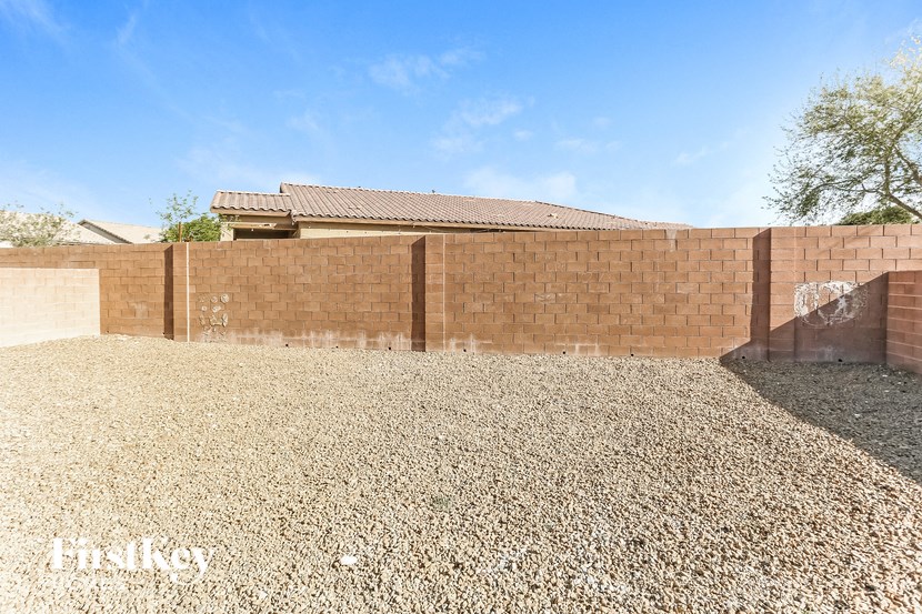A gravel yard with a brick wall and a building in the background.