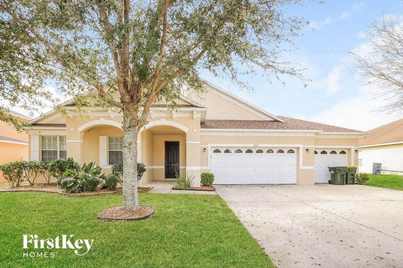 a home with a white garage door and a tree in the yard