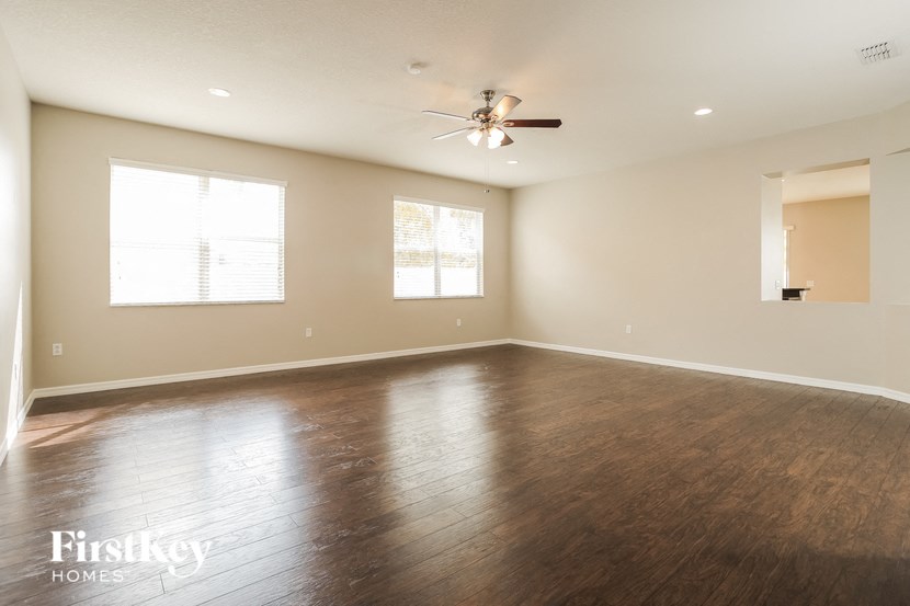 an empty living room with wood floors and a ceiling fan