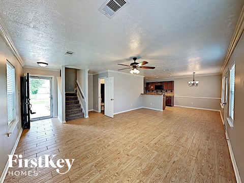 an empty living room with wood floors and a ceiling fan