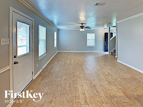 an empty living room with a wood floor and a ceiling fan