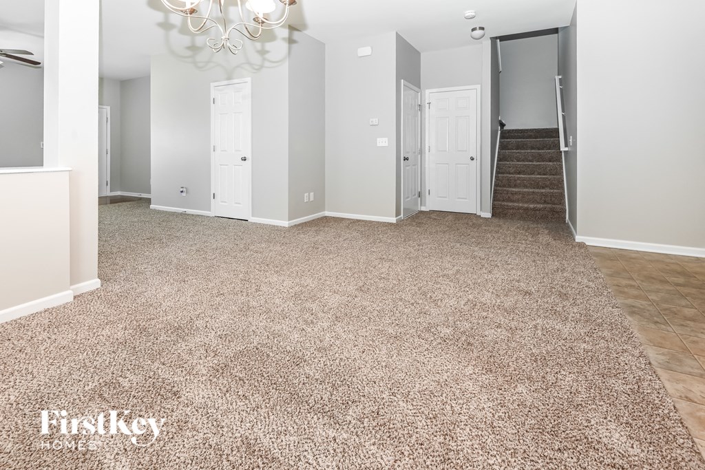 a living room with a carpeted floor and a staircase