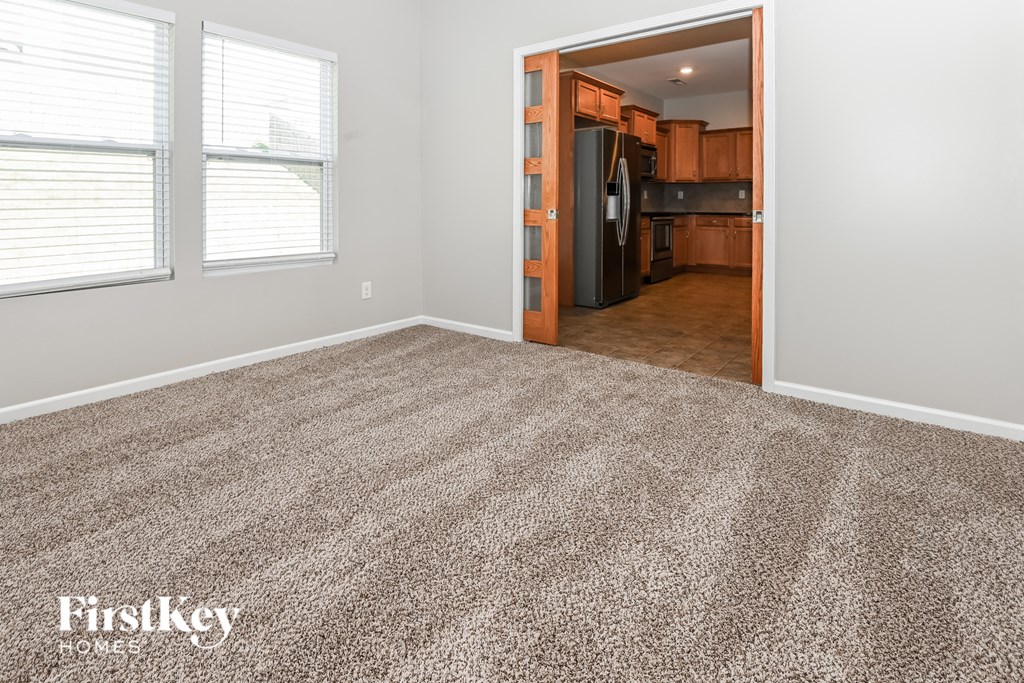 a living room with a carpeted floor and a kitchen