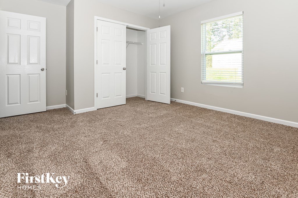 a room with carpet and two doors and a window