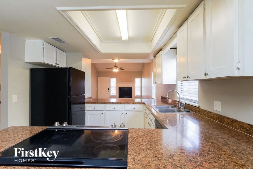 A kitchen with a black refrigerator and a countertop with a FirstKey Homes logo.