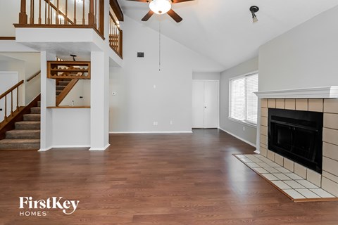 A spacious living room with a fireplace and a staircase.