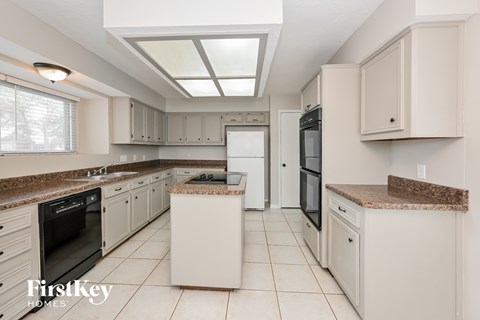 A kitchen with white cabinets and appliances.