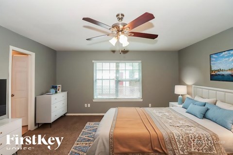 A bedroom with a large bed and a ceiling fan.