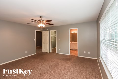 A spacious room with a ceiling fan and a carpeted floor.