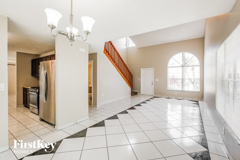 an empty kitchen and living room with a staircase and a window