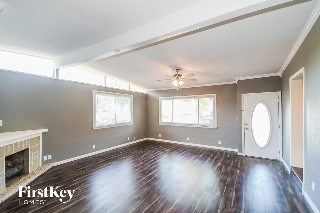 an empty living room with wood floors and a ceiling fan