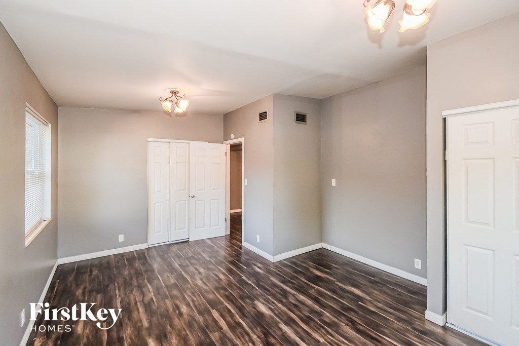 an empty living room with wood flooring and white doors