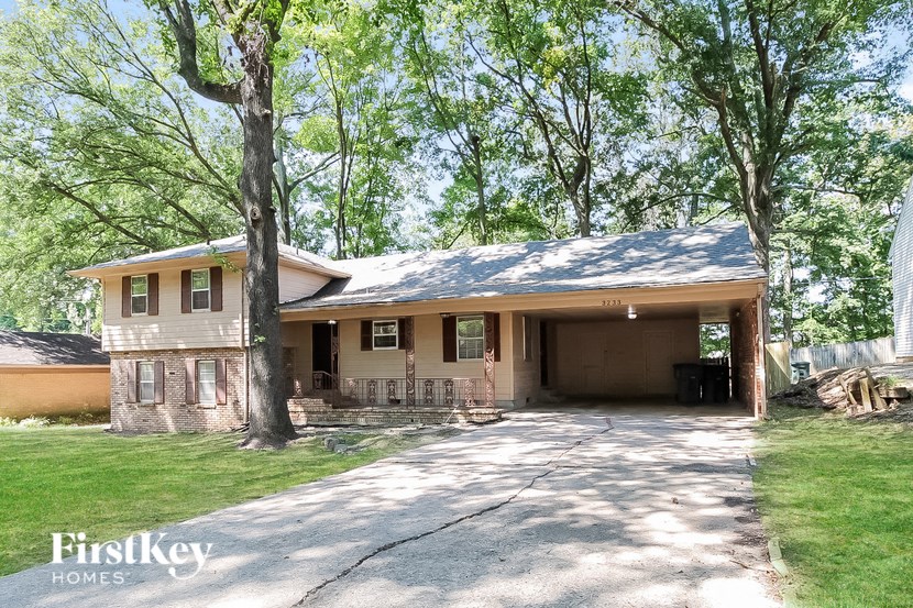 a house with a driveway and a porch with trees
