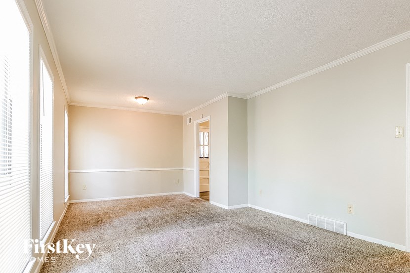 an empty living room with white walls and carpet