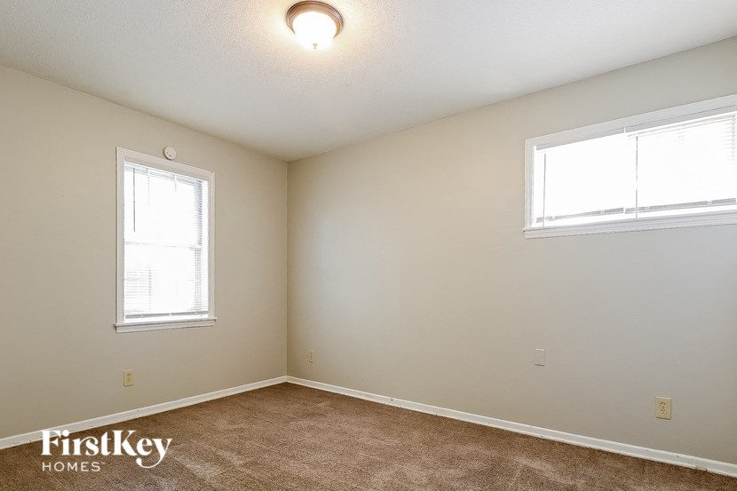 a bedroom with two windows and a carpeted floor