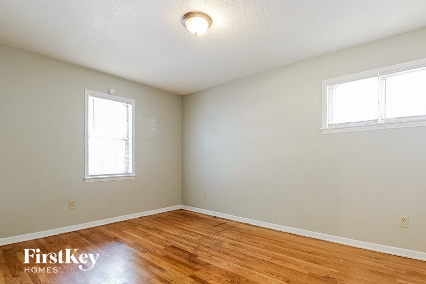 an empty room with a wooden floor and two windows