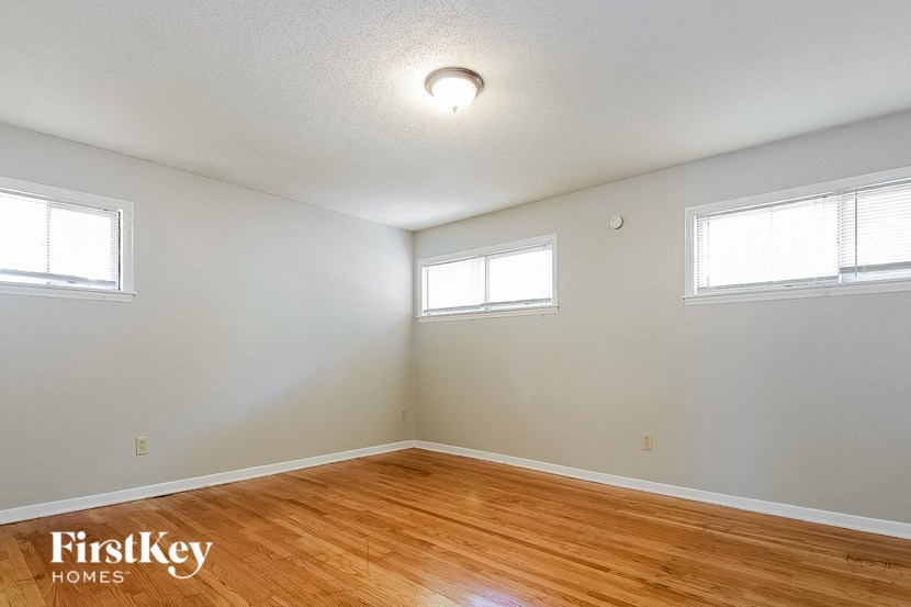 an empty room with a hard wood floor and two windows