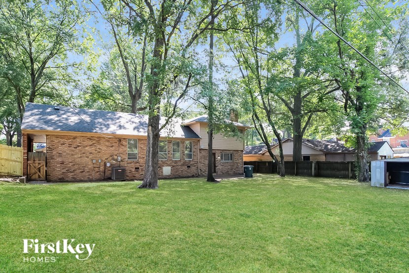 a brick house in the middle of a yard with trees