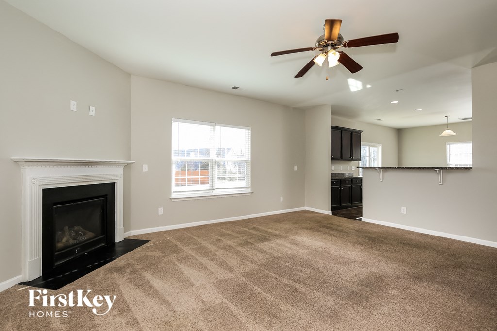 A spacious living room with a fireplace and a ceiling fan.