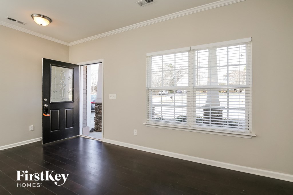 A room with a black door and a window with white blinds.