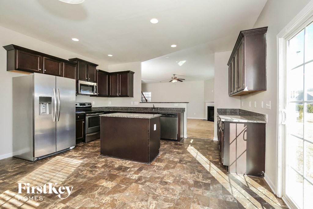 A kitchen with a refrigerator, microwave, and oven.
